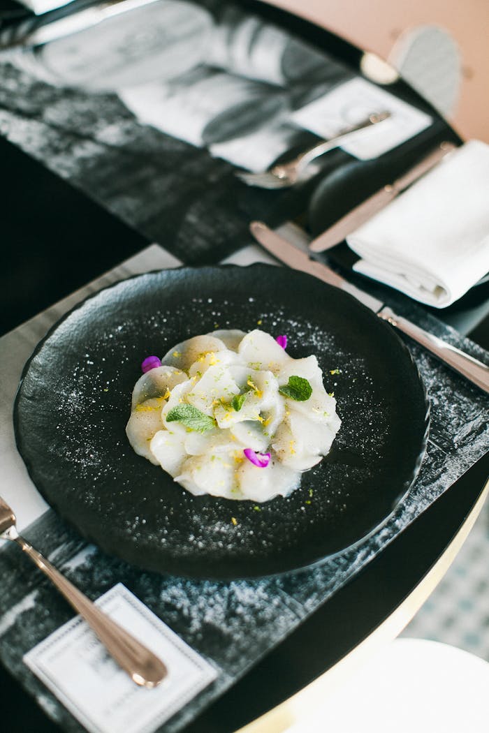 Elegant plate of sashimi garnished with greens and flowers, ideal for Asian cuisine themes.